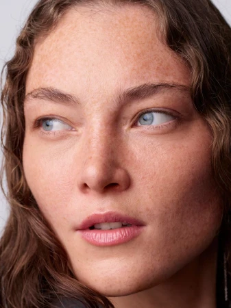 Close-up portrait of a woman with freckles and blue eyes looking away for Double Magazine shot by Horst Diekgerdes.