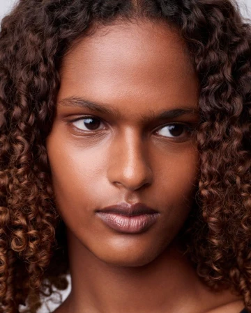 Close-up portrait of a woman with curly brown hair and neutral expression for Double Magazine