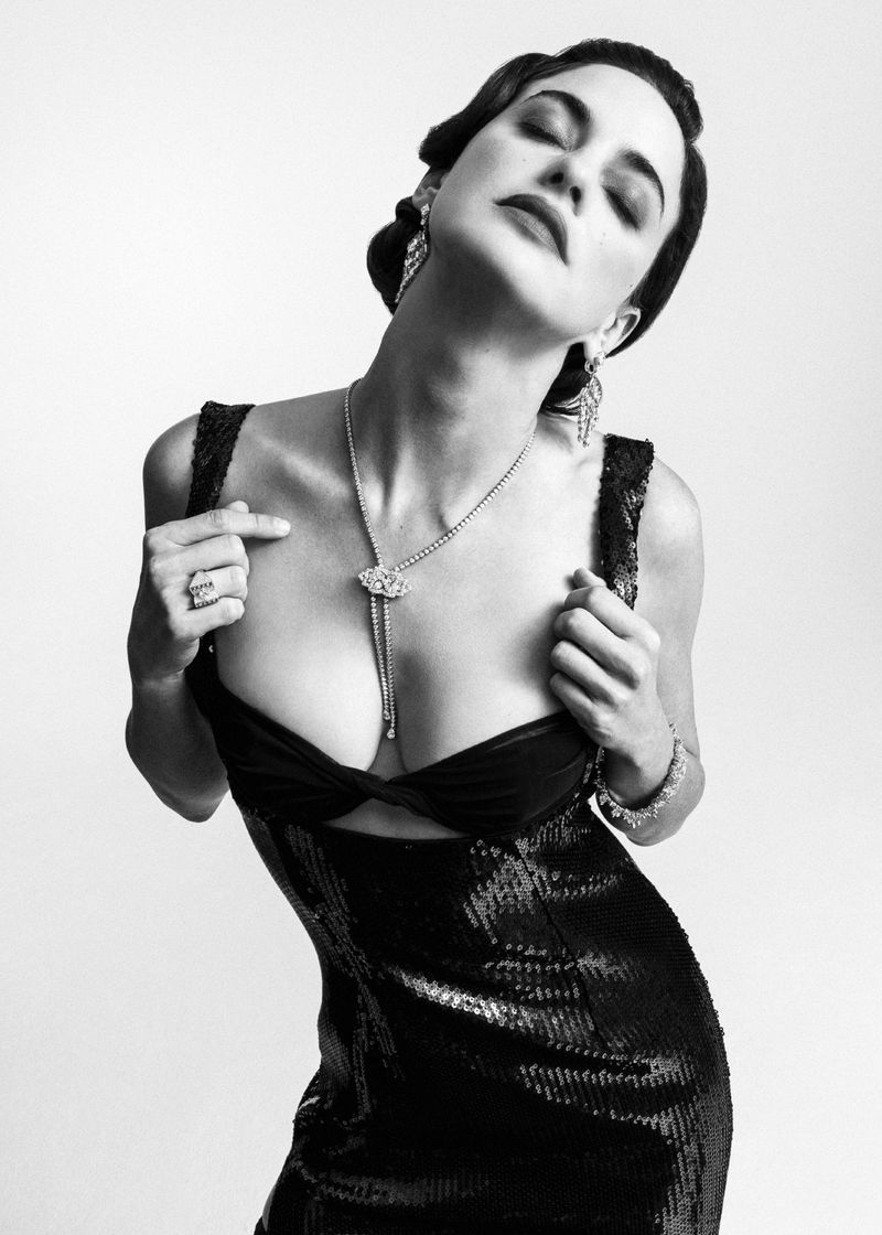 Model in a black sequin dress with diamond jewelry posing against a plain background for 5ELEVEN Magazine