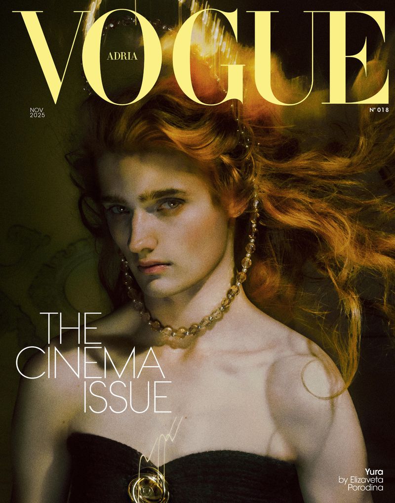 Vogue Adria cover featuring a model with red hair wearing a black strapless top and gold jewelry on a dark backdrop, November 2025 issue.