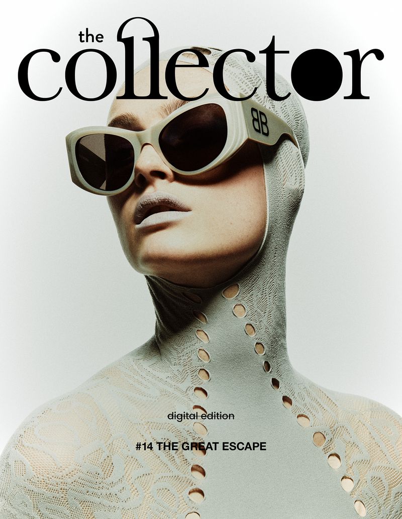 Magazine cover featuring a person wearing a patterned hood and oversized sunglasses, with a light grey color scheme and minimal background.