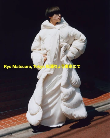 Editorial shot of a person in a large white puffer coat walking down a city street, with a dark background and good lighting.