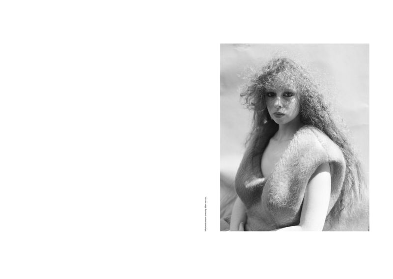 Black and white portrait of an adult female with long, curly hair wearing a fur garment against a blurred outdoor background.