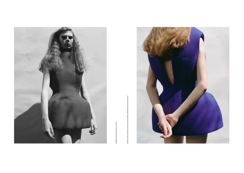 Editorial fashion shot of two women modeling minimalist dresses, one in black and white and the other in cobalt blue, in a studio setting.