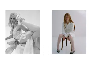 Two fashion models posing in a studio, one lying down holding a shoe up and one seated on a wooden chair against white walls.