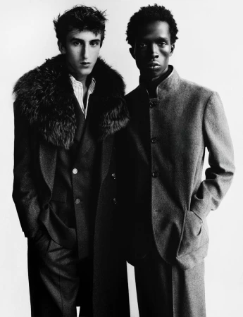 Two male models in dark tailored coats posing against a plain white background for Harper's Bazaar France Homme.