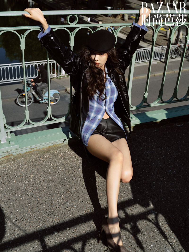 Woman in black leather jacket and newsboy cap posing on a bridge for Where Paris Whispers editorial by Harper's Bazaar China.