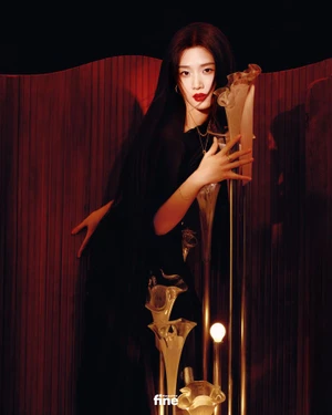 Woman in dark clothing posing with metallic sculptural flower props against a deep red textured backdrop