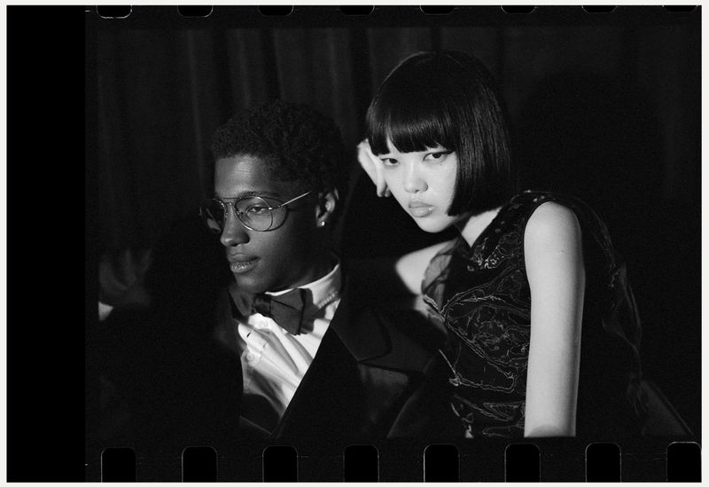 Black and white portrait of an adult male in a bow tie and an adult female with a bob haircut, posing in front of a dark background.