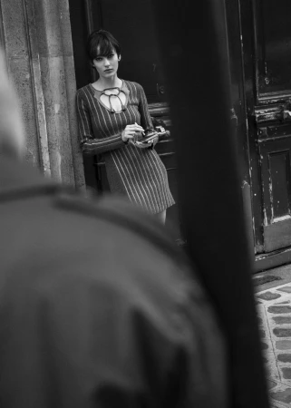 Model in a striped dress leaning against a doorway in a black and white editorial photograph for 5ELEVEN Magazine