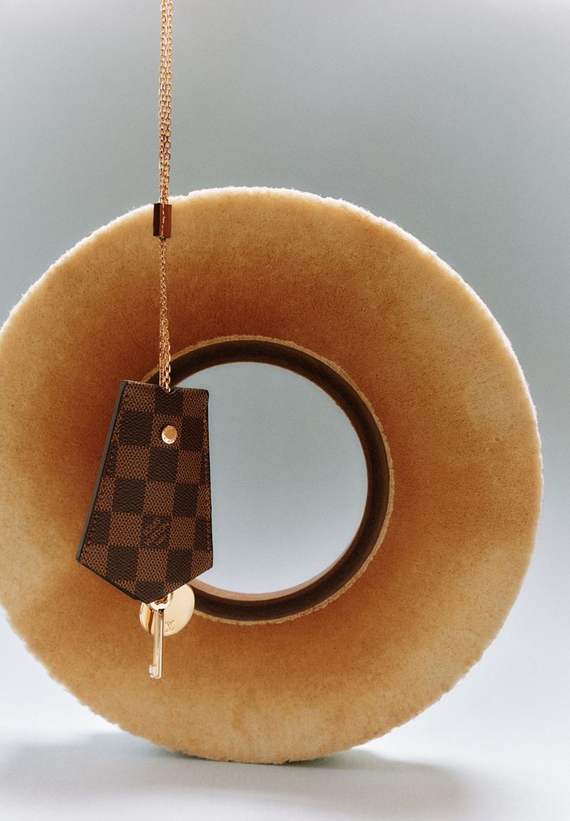 Luxury fashion: A round furry hat with a designer key chain, featuring a leather tag with a brown checkerboard pattern and a golden key.