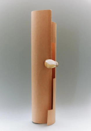Abstract shot of a peach-colored scroll-like cylinder with a metallic, rounded accent, set against a plain gray backdrop, minimalist design.