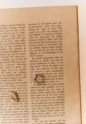 Two gold rings resting on an open vintage book page with printed French text.