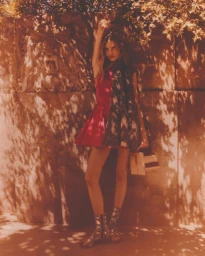 Model Cara Schädel in a pink dress standing against a stone wall with dappled sunlight for Harper's Bazaar España