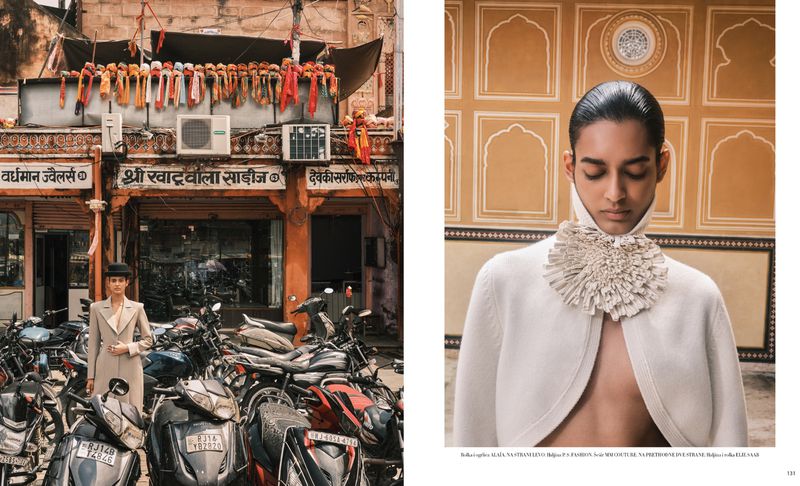 Fashion editorial image in Jaipur, India with a person in a beige coat and hat in front of parked motorbikes and a building with signage.