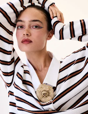 Model Sasha Kichigina wearing a striped sweater with a floral brooch posing for Harper's Bazaar Espana