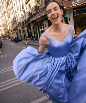 Model laughing while running down a city street wearing a vibrant blue gown for Telegraph Luxury