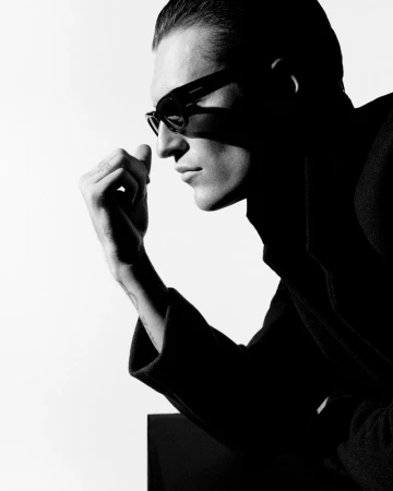 Black and white profile portrait of model Myles Crosby wearing dark sunglasses and a coat for Zara Night A/W 25.