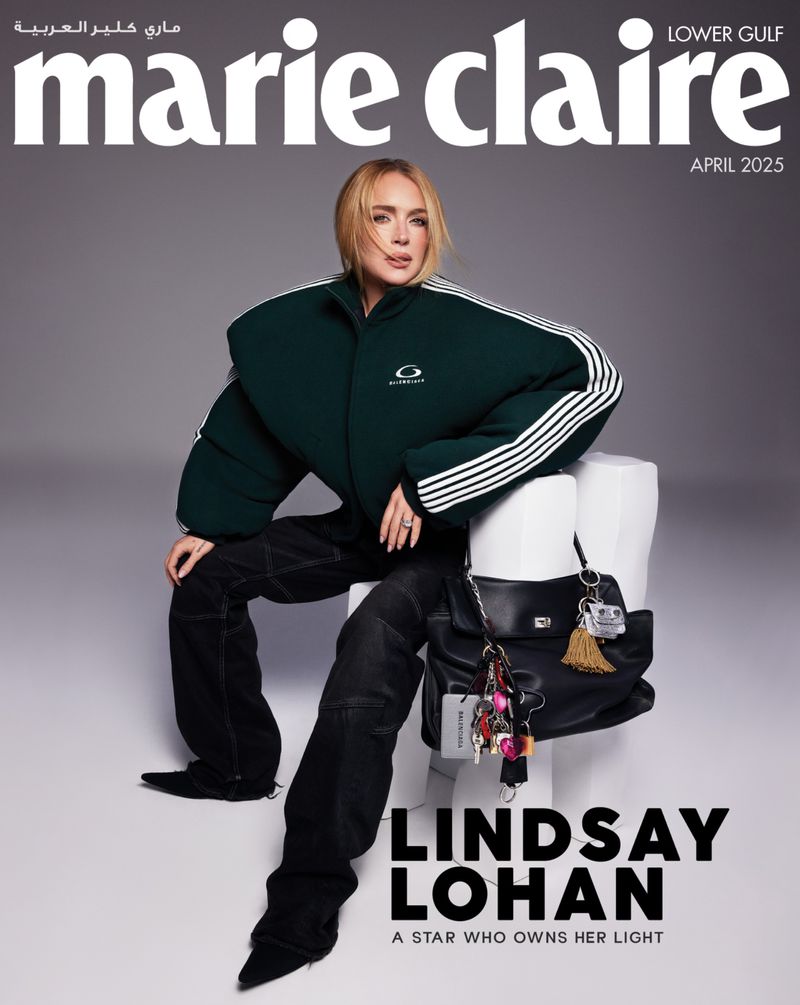 Magazine cover featuring Lindsay Lohan in a green jacket and black pants, seated on a white stool against a gray backdrop.