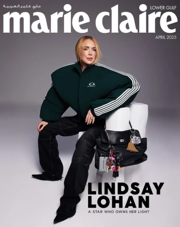 Magazine cover featuring Lindsay Lohan in a green jacket and black pants, seated on a white stool against a gray backdrop.