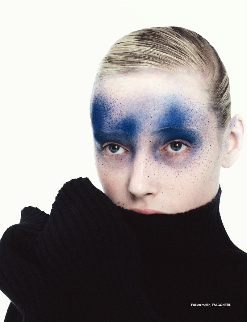 Summer Dirx with dramatic blue eye makeup wearing a black ribbed turtleneck pulled over her chin against a white backdrop.