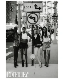 Four female models posing on a New York city sidewalk beneath street signs in a black and white fashion editorial photograph.