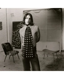 Model with long dark hair wearing a striped shirt and polka dot scarf in a studio setting