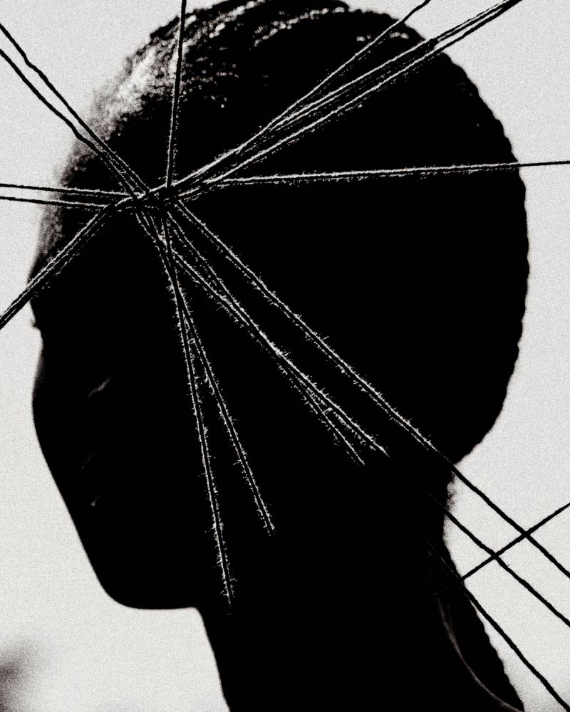 Monochromatic portrait of an African American woman's profile with thin white spikes radiating from her head against a soft grey backdrop.
