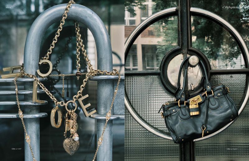 Close-up product shot featuring gold necklaces with the word 'HOPE' on a metal railing and a black leather purse hanging on a metal door.