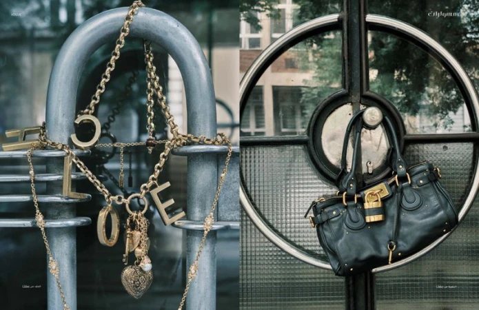 Close-up product shot featuring gold necklaces with the word 'HOPE' on a metal railing and a black leather purse hanging on a metal door.