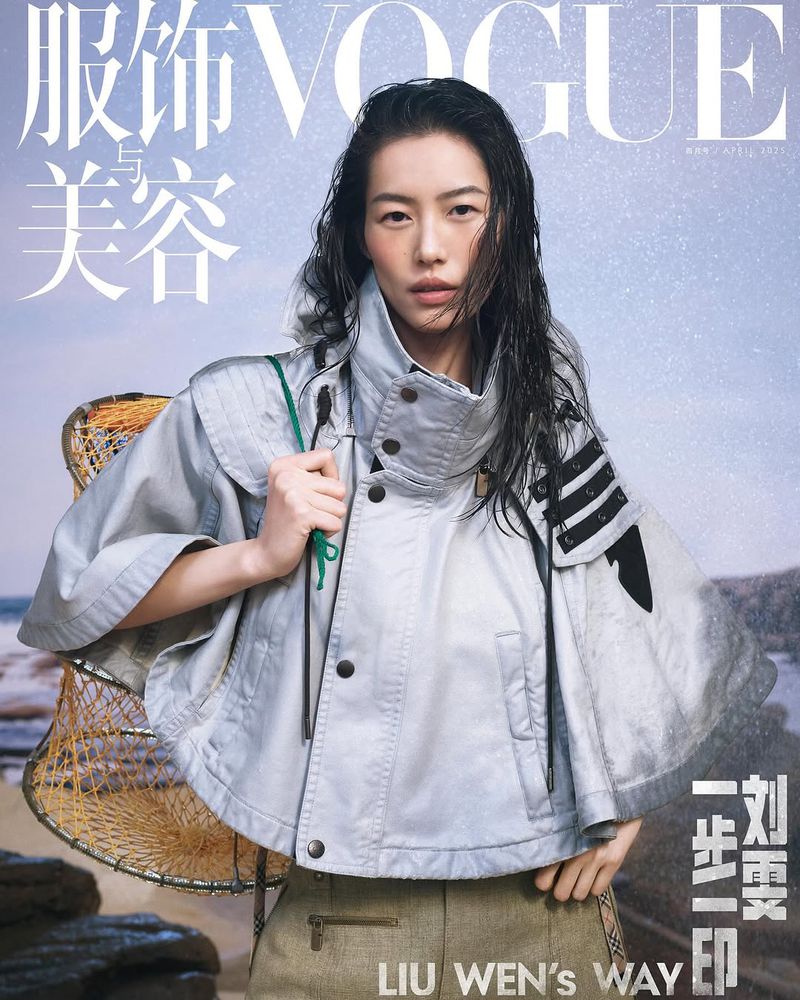 Vogue cover featuring an Asian female model in a silver jacket with wet hair, against a rocky beach background with fishing gear.