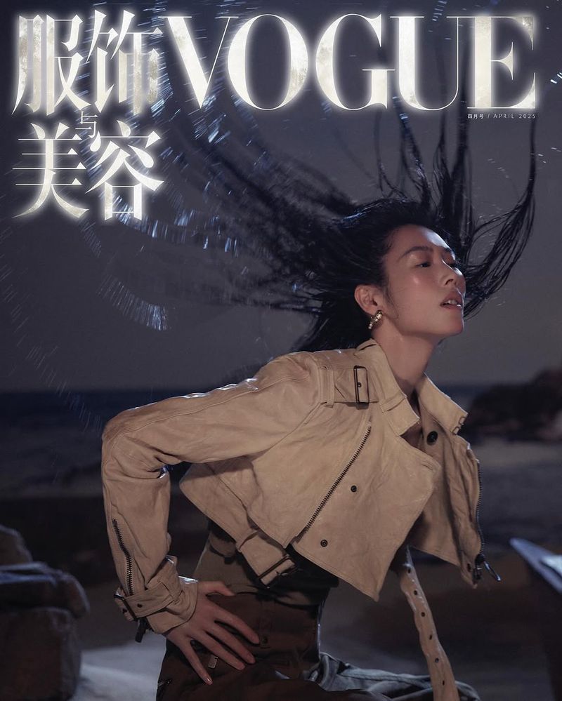 Vogue cover featuring a woman with wind-swept black hair wearing a beige cropped jacket against a blurred beach background.