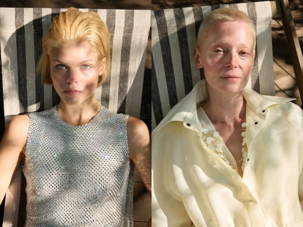 Two women with short blond hair pose in a close up shot, one wearing a shiny silver top and the other in a sheer, light yellow top.