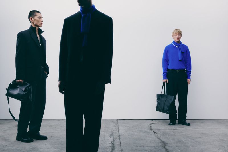 Three male models in dark tailored clothing against a white wall and concrete floor, captured by Alvaro Pereña for Zara.