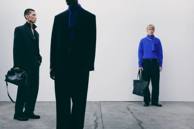 Three male models in dark tailored clothing against a white wall and concrete floor, captured by Alvaro Pereña for Zara.
