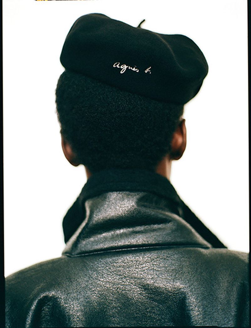 Back of person with black beret that says 'agnes b.' and a black leather jacket, in a fashion or beauty editorial shot.