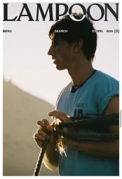 Model Clément Laguardia in profile holding a thick rope and wearing a light blue t-shirt against a sand dune backdrop.