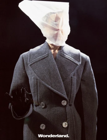 Fashion shot of person in grey coat with bag over head in front of a black background. The word Wonderland is at the bottom.