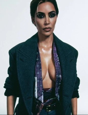 Kim Kardashian wearing an open dark charcoal coat and patterned purple silk scarf against a white studio background.