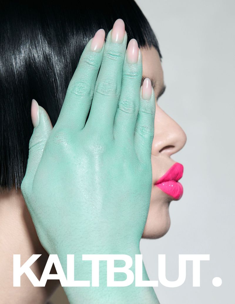 Close-up side profile of a woman with short black hair, bright pink lips, and mint-green painted hand covering part of her face.