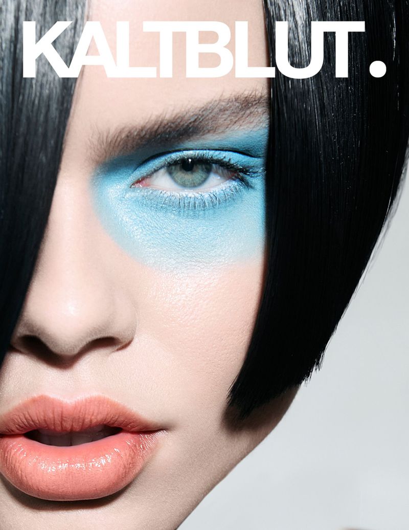 Close-up portrait of a woman with creative blue eyeshadow, black hair, and glossy coral lipstick, featured on a Kaltblut magazine cover.
