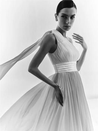 Model Mili Boskovic in a white pleated gown with a sash for Elisabetta Franchi x Pronovias S/S 26