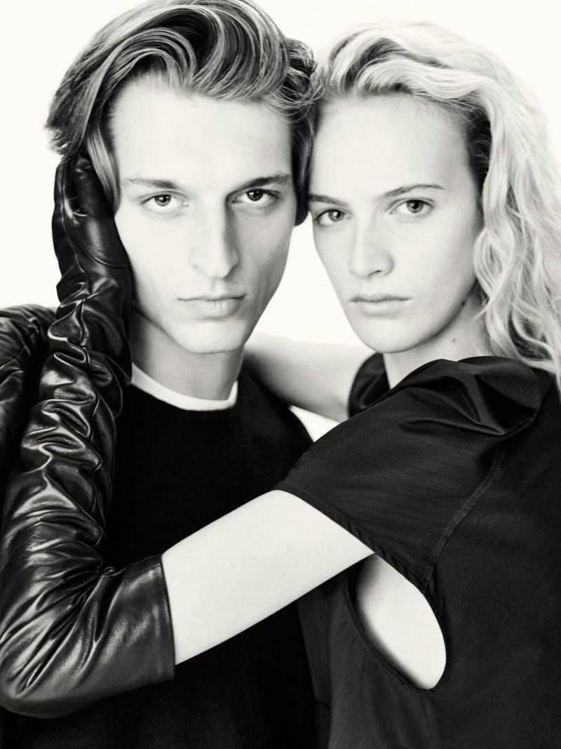 Monochrome portrait of a stylish adult couple with fair skin. The man has one hand in a long leather glove covering the woman's shoulder.