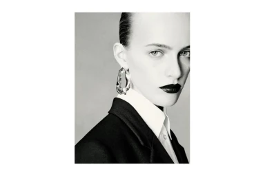 Close-up portrait of a model wearing a dark blazer, white shirt, and sculptural silver earring for Massimo Dutti.
