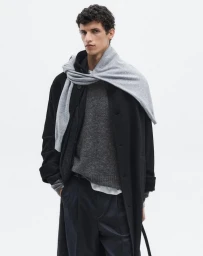 Model wearing a black coat and grey scarf against a plain white studio background for Massimo Dutti