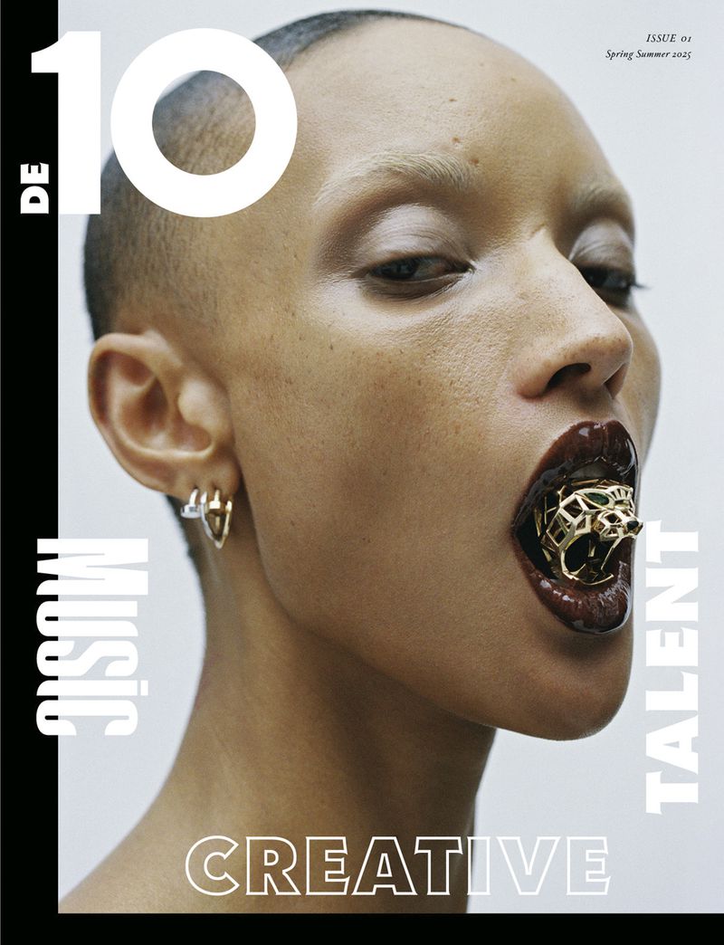 Close-up of a model with dark lipstick and a gold grill, a magazine cover with the words 'MUSIC' and 'CREATIVE' printed on the side.