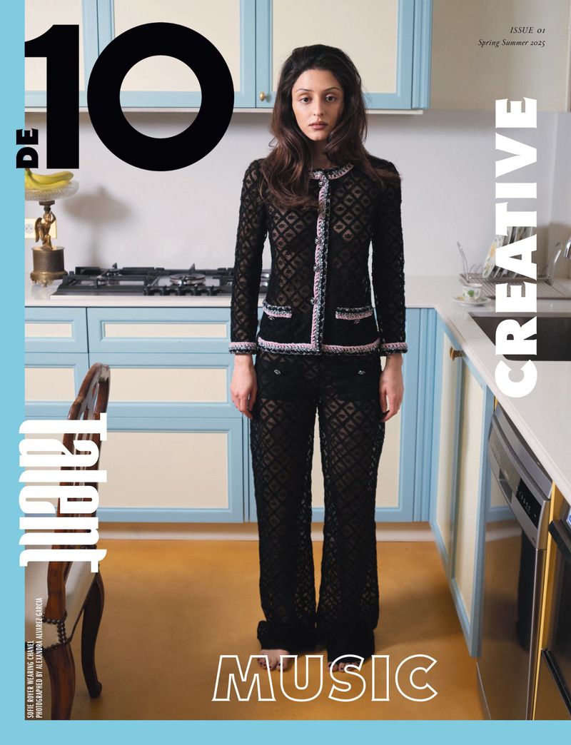 Magazine cover featuring a woman in a black lace suit standing in a kitchen, alongside text elements like the magazine title.