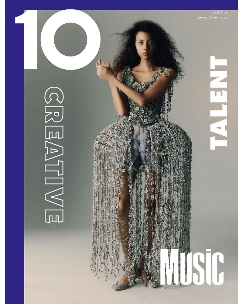 Magazine cover featuring a young, dark-haired woman in a textured couture dress with heavy fringe, against a gradient gray background.