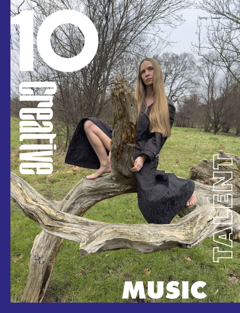 Magazine cover features woman in black coat posing on a log in a grassy field with bare trees, under a cloudy sky. '10 Creative Talent Music'.