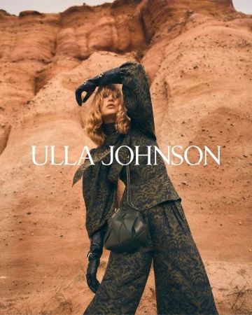 Fashionable woman poses in a patterned green pantsuit with a matching purse against a desert canyon backdrop for Ulla Johnson.